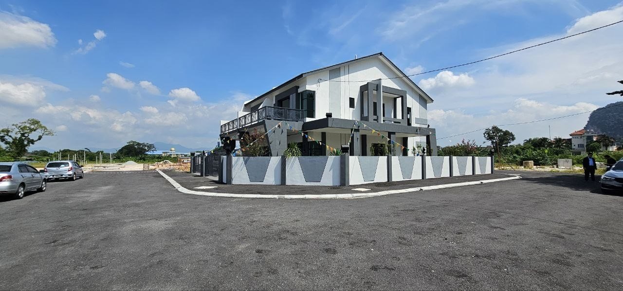 Corner double-storey terrace show unit and estate road with limestone hills behind at Ampang Cove by LYS Realty Sdn Bhd, Ampang, Ipoh, Perak